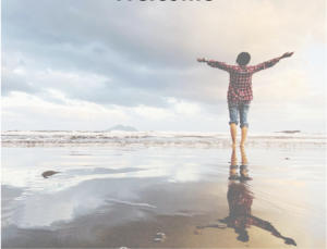 Person standing the beach, arms opened wide reaching up to the sky